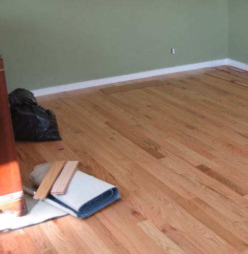 Room with new hardwood flooring being installed, with surrounding walls painted a light green color.